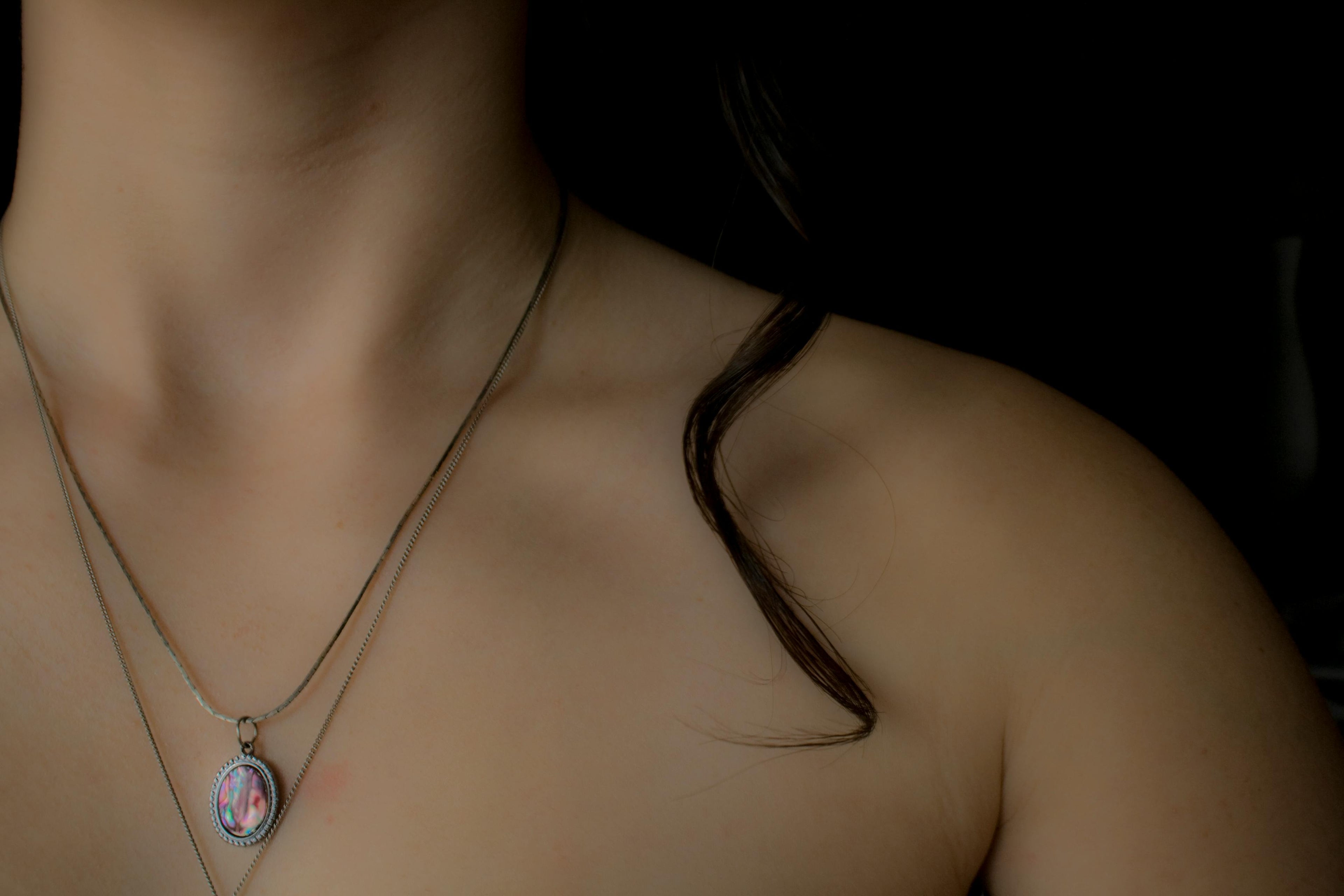 Necklace with a pendant worn by a person against a dark background