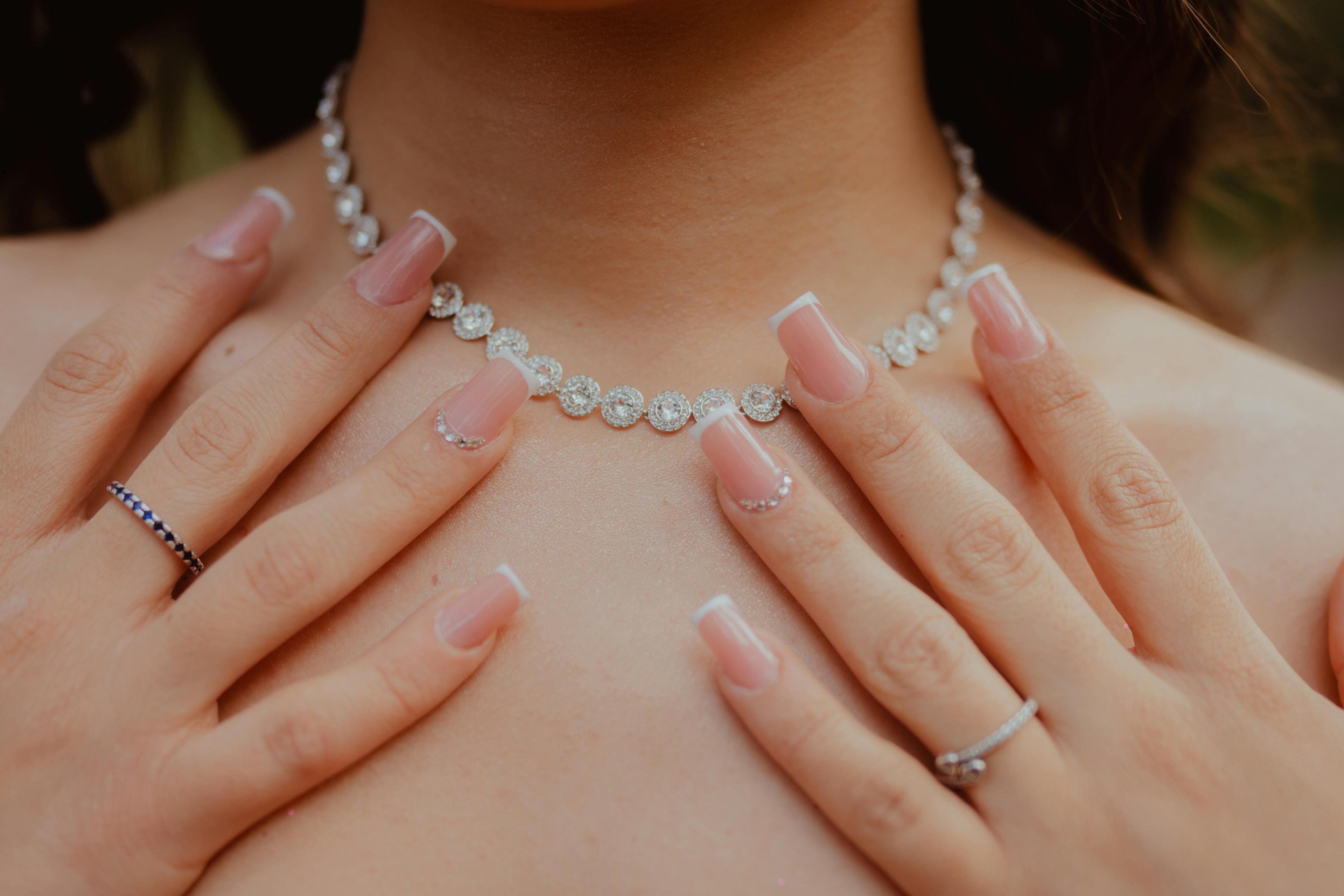 Pearl necklace worn by a person with hands gently touching the chest.